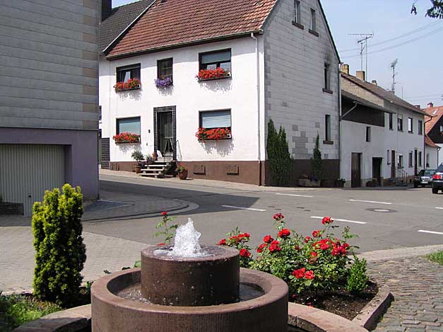 Der Dorfbrunnen in Schallodenbach mit Haus Hemmer in der Gro&szlig;en Gasse